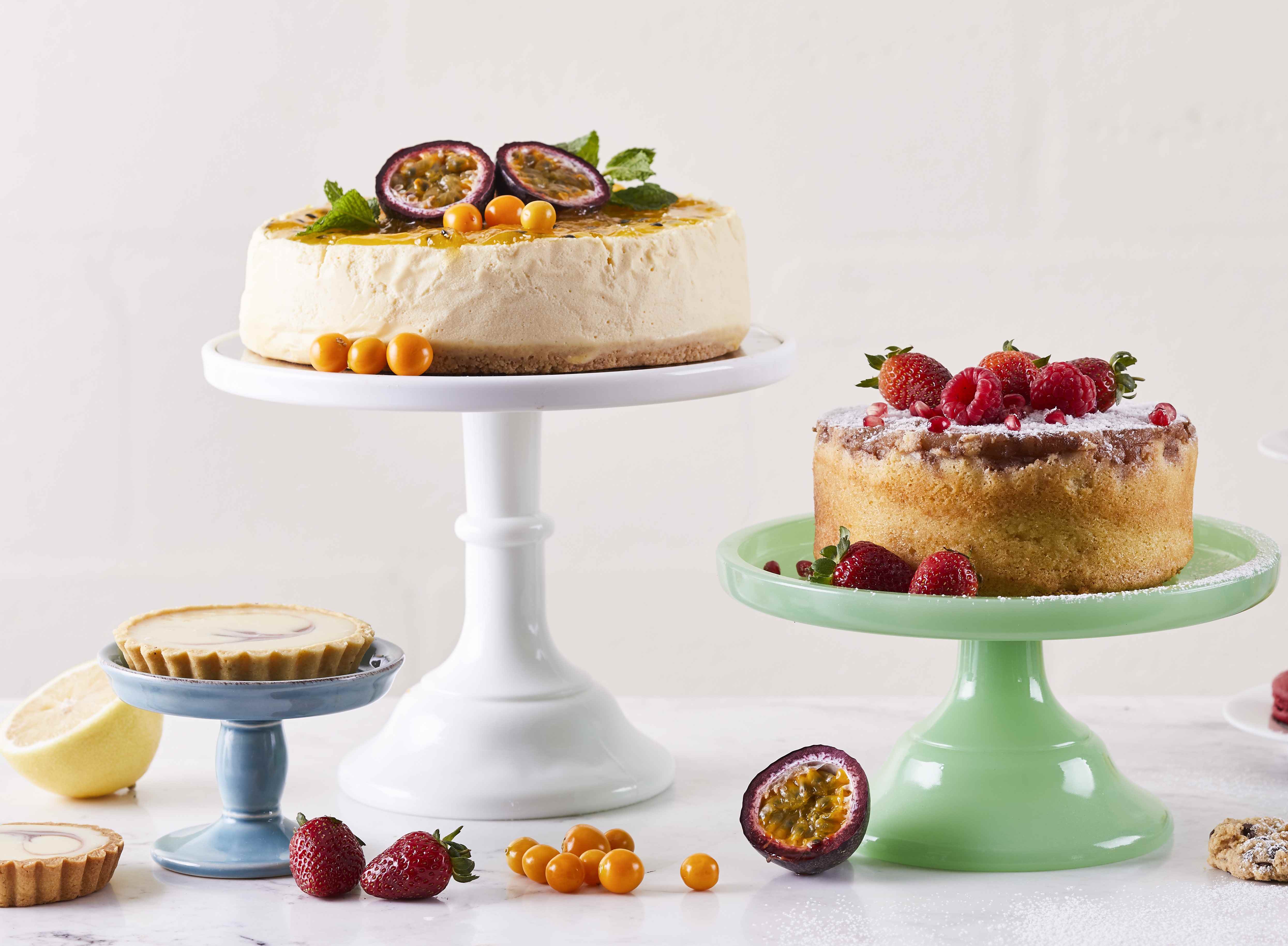 Cakes and tarts displayed on cake stands with fresh fruit